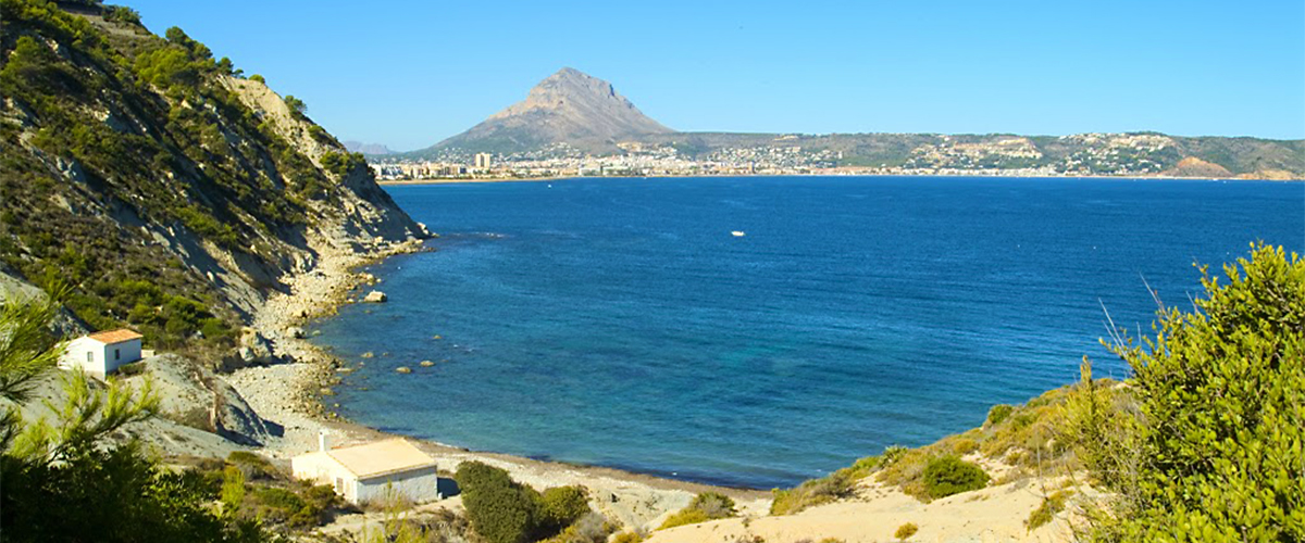 Jávea Turismo - Blick auf Cala Sardinera und Montgó im Hintergrund in Jávea.